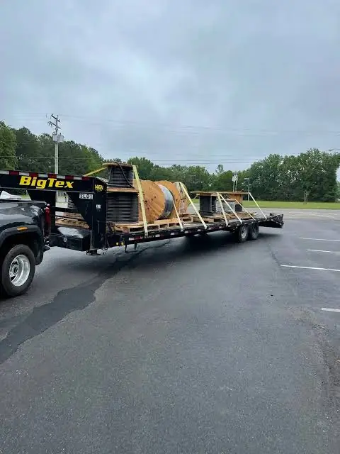 Cable reels secured to a gooseneck flatbed trailer attached to a pickup truck.