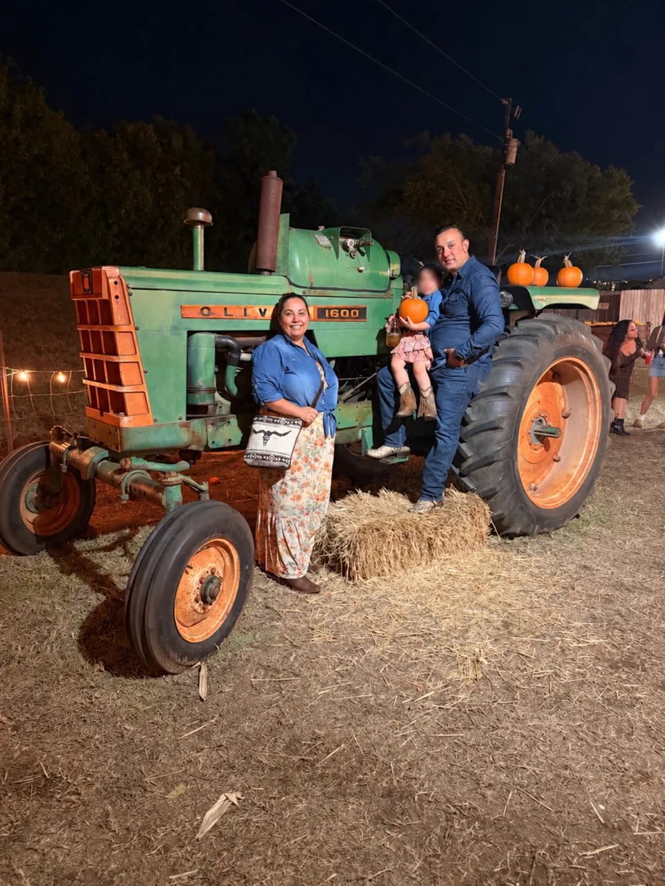 Joey and Diane with their daughter Joanna beside a vintage tractor.